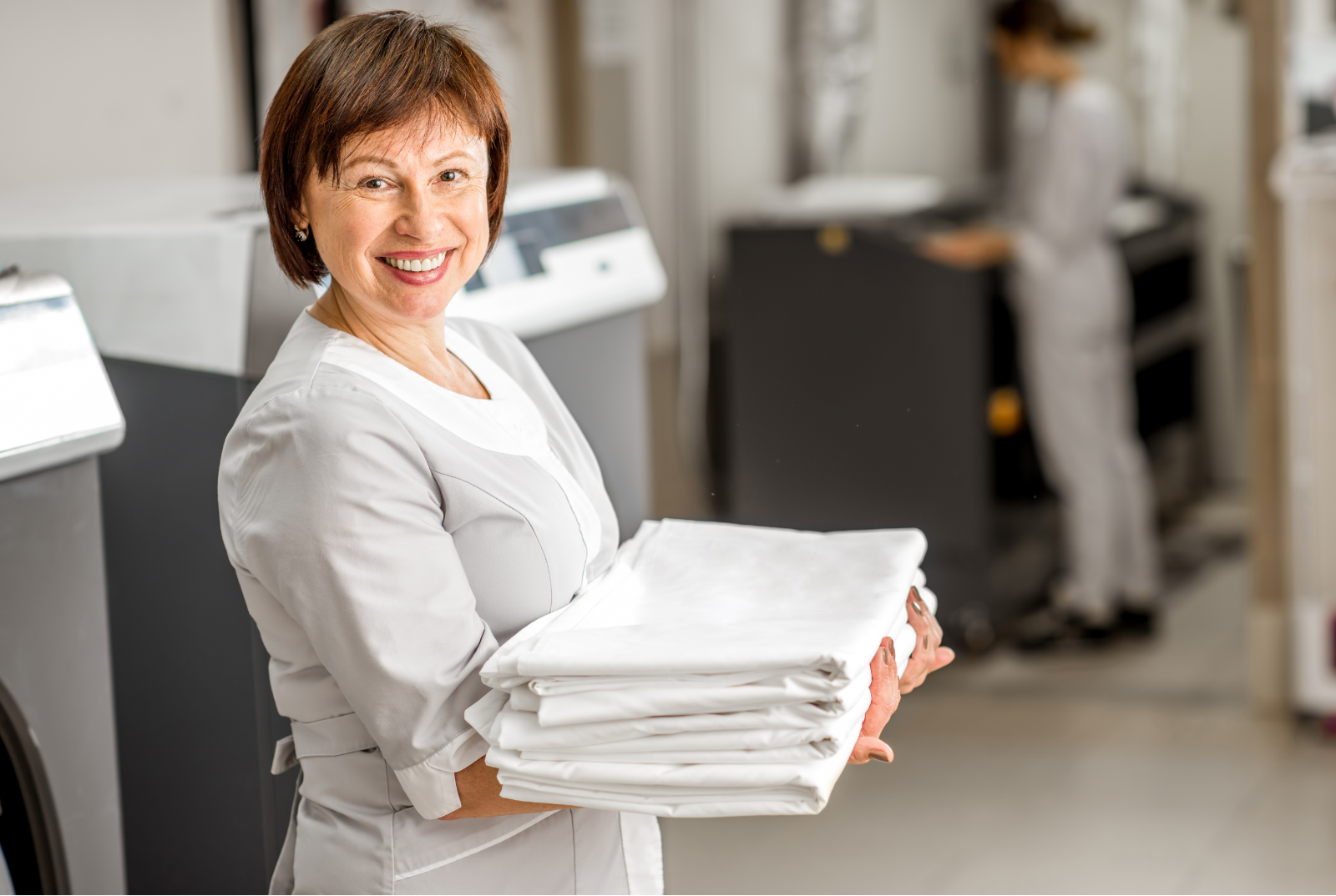 Laundry worker carrying freshly pressed table linen