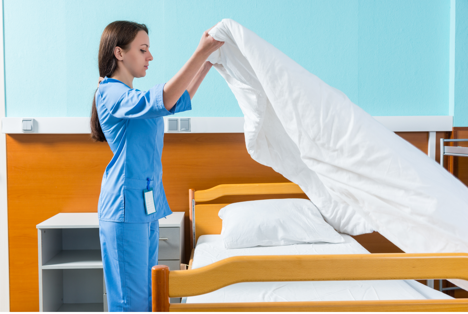 Nurse making a hospital bed with fresh white linen